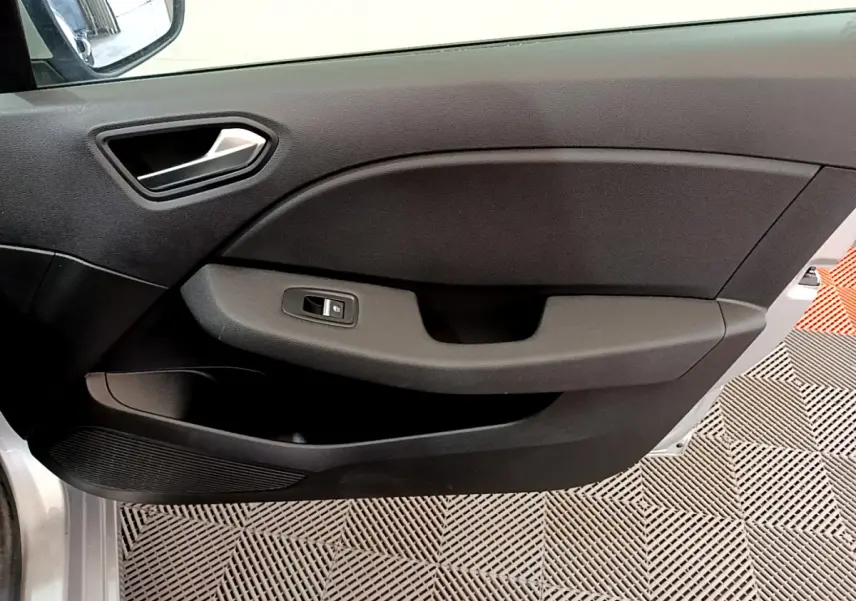 Vue intérieure du panneau de porte avant gauche de la Renault Clio Business TCe 100 gris clair, avec commande de fenêtre électrique.