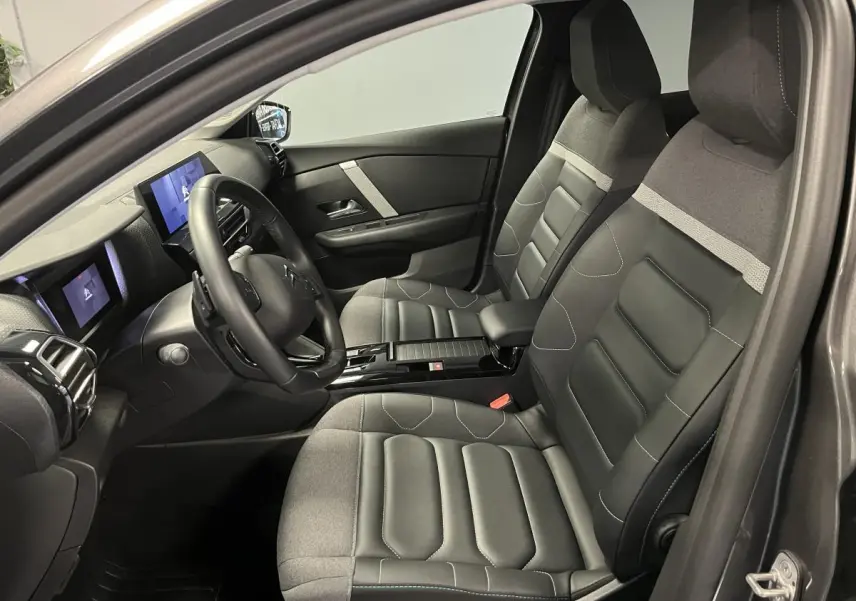 Intérieur avant de la Citroën C4 X gris 2024, sièges Advanced Comfort bicolores et tableau de bord avec écran tactile.