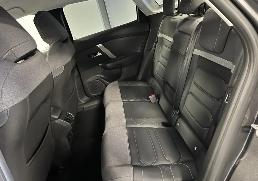 Vue intérieure arrière côté droit du Citroën C4 X 2024 gris, sièges Advanced Comfort en tissu et toile enduite noir et gris.