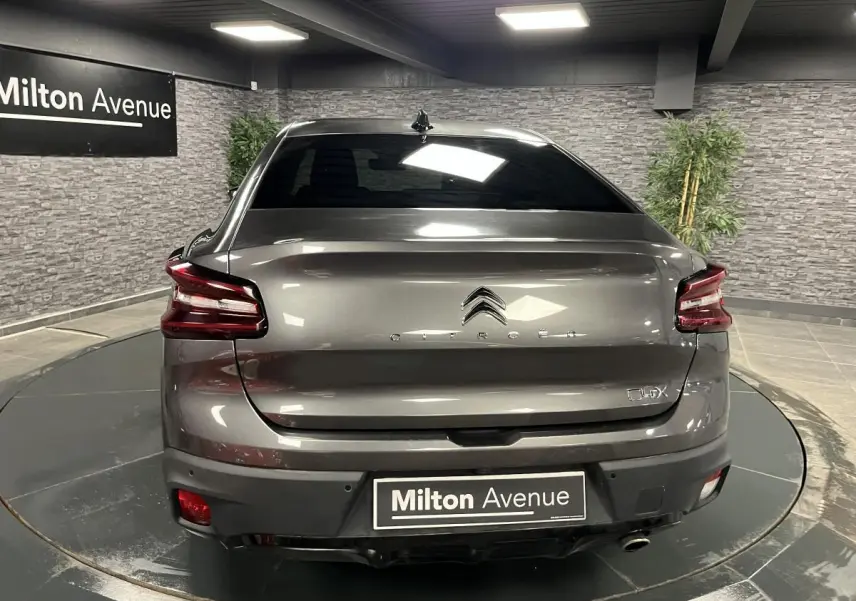 Vue arrière d'une Citroën C4 X gris métallisé 2024 avec feux LED et logo centré dans un showroom.
