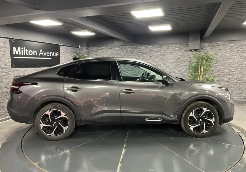 Profil côté gauche du Citroën C4 X gris métallisé 2024 avec jantes alliage 18'' et lignes fluides élégantes.