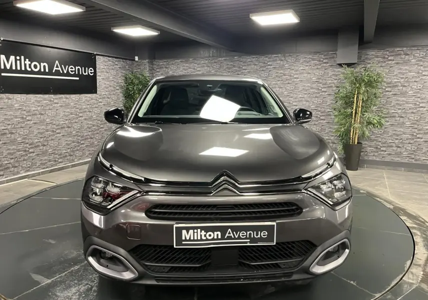 Vue frontale d'une Citroën C4 X gris métallisé 2024 avec signature lumineuse en V et calandre noire brillante.