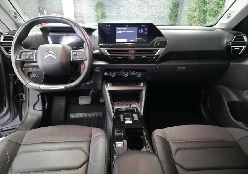 Intérieur noir du Citroën C4 X 2024, vue frontale du tableau de bord avec écran tactile et volant multifonction.