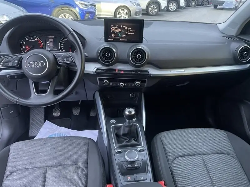 Vue intérieure de l'Audi Q2 30 TFSI 116 SPORT LIMITED 2020, tableau de bord et boîte manuelle au centre, sièges gris.