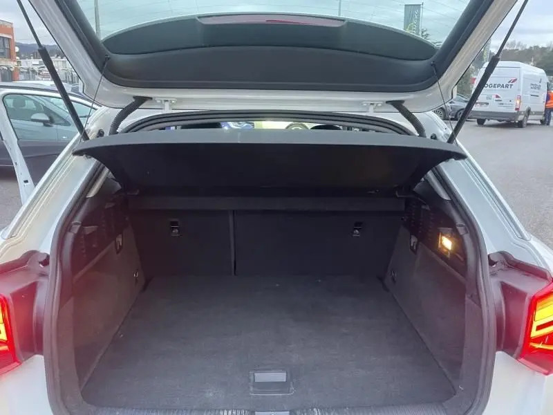 Coffre ouvert vu de l'arrière d'un Audi Q2 blanc 30 TFSI 116 SPORT LIMITED 2020, intérieur noir et éclairage latéral.