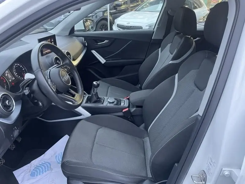 Vue intérieure côté conducteur de l'Audi Q2 blanc 30 TFSI 116 SPORT LIMITED 2020 avec boîte manuelle et sièges noirs.