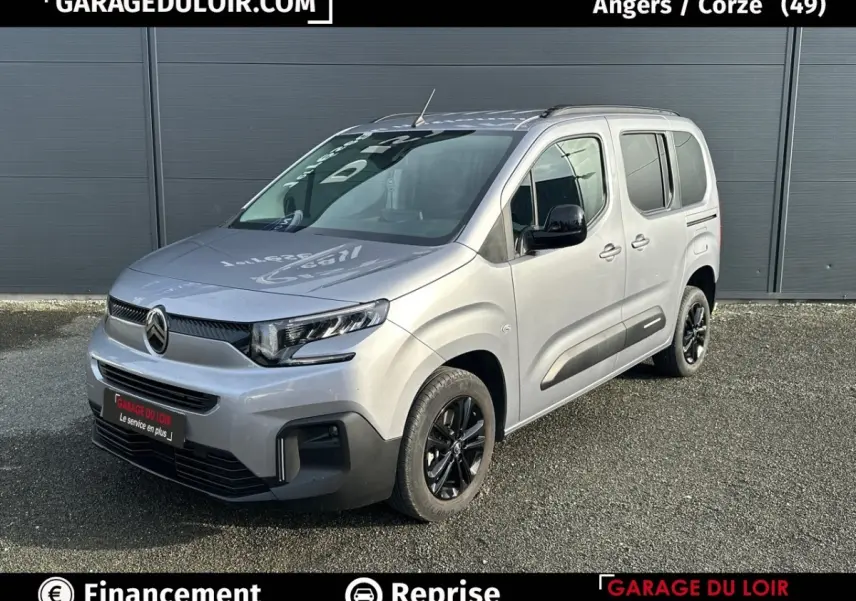Vue 3/4 avant droite d'un Citroën Berlingo gris clair 2024 avec jantes noires et protections latérales noires.