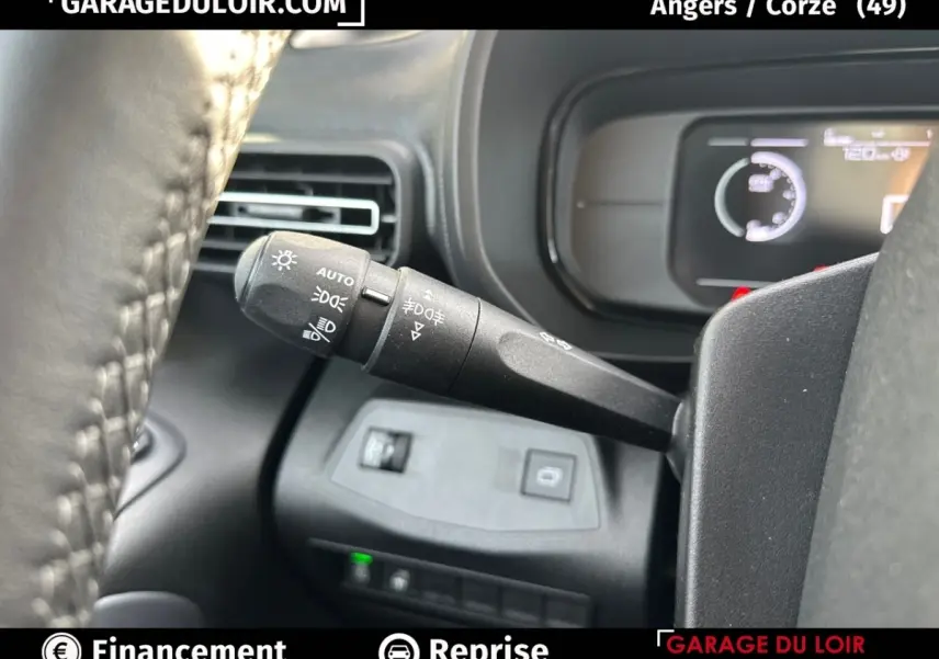Gros plan sur la manette des feux et clignotants à gauche du volant cuir dans un Citroën Berlingo gris clair 2024.