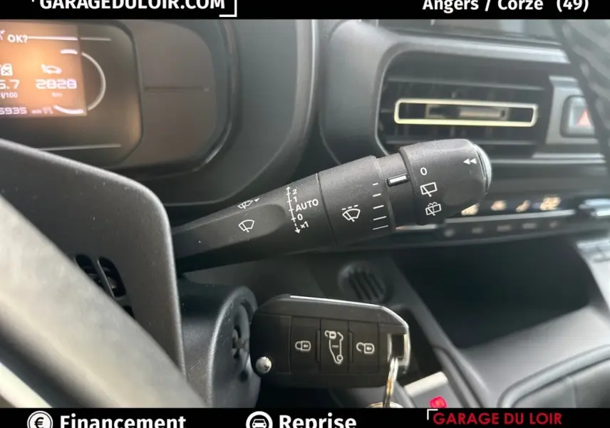 Gros plan sur la commande d’essuie-glace et la clé insérée dans le contact du tableau de bord noir du Citroën Berlingo gris clair.