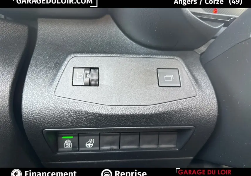 Gros plan sur les commandes noires du tableau de bord du Citroën Berlingo gris clair, avec réglage des phares et bouton de verrouillage.
