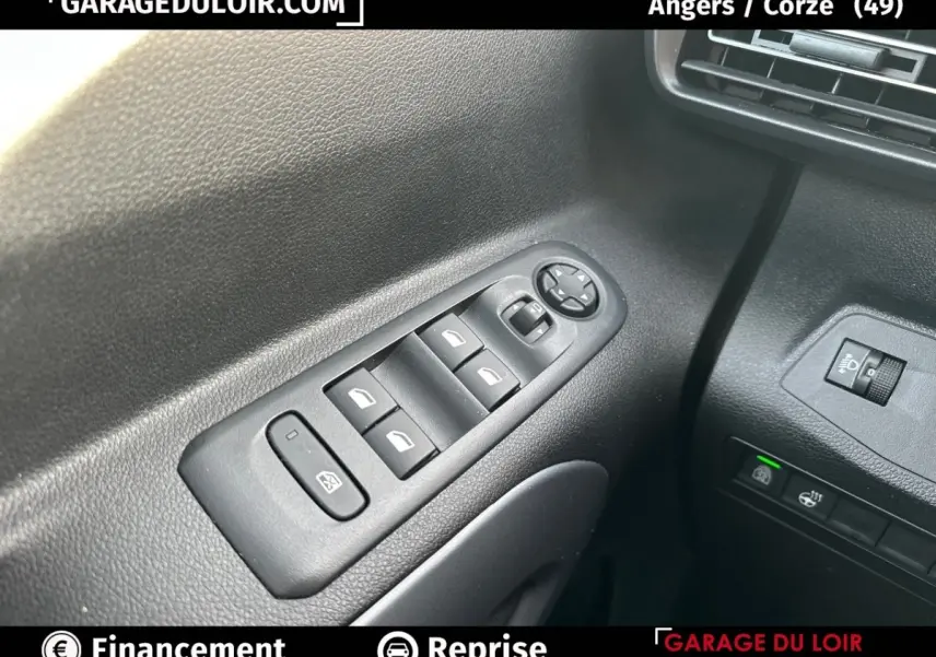 Gros plan sur les commandes des vitres électriques et réglages des rétroviseurs côté conducteur du Citroën Berlingo gris clair 2024.