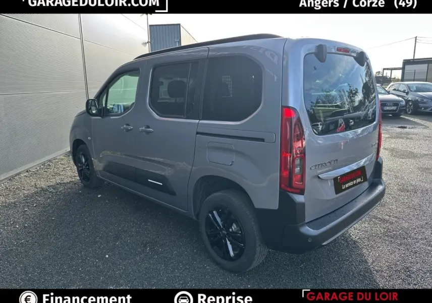 Vue 3/4 arrière droite d'un Citroën Berlingo gris clair avec vitres teintées et jantes noires.