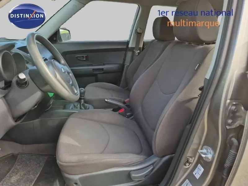 Vue intérieure côté conducteur du Kia Soul 2010, sièges tissu gris et volant avec boîte manuelle visible.