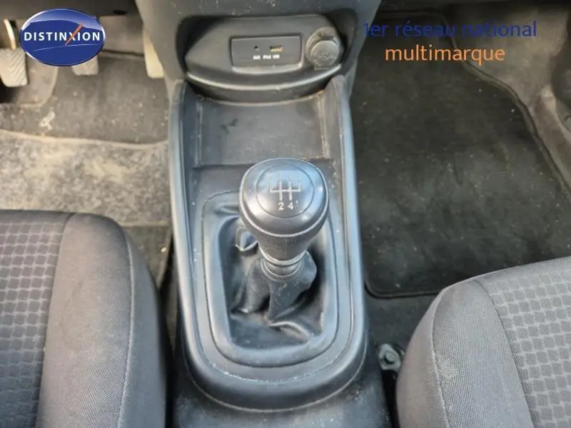 Vue rapprochée du levier de vitesses manuel noir au centre de la console d'une KIA SOUL 2010, sièges gris visibles.