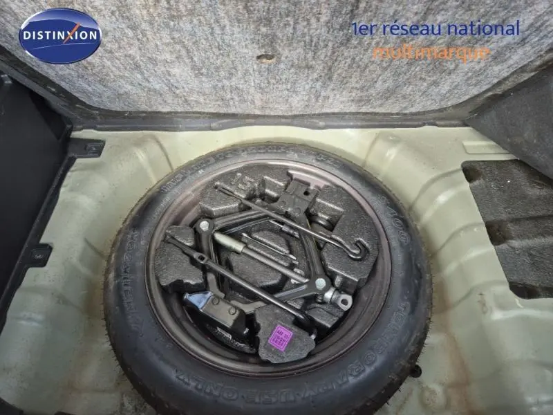 Vue rapprochée de la roue de secours noire et des outils de bord dans le coffre d'une KIA SOUL 2010.