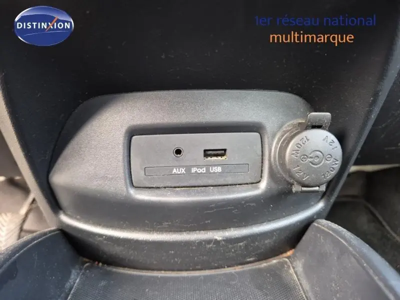Vue rapprochée de la console centrale noire du Kia Soul 2010 montrant les prises AUX, iPod, USB et une prise 12V.