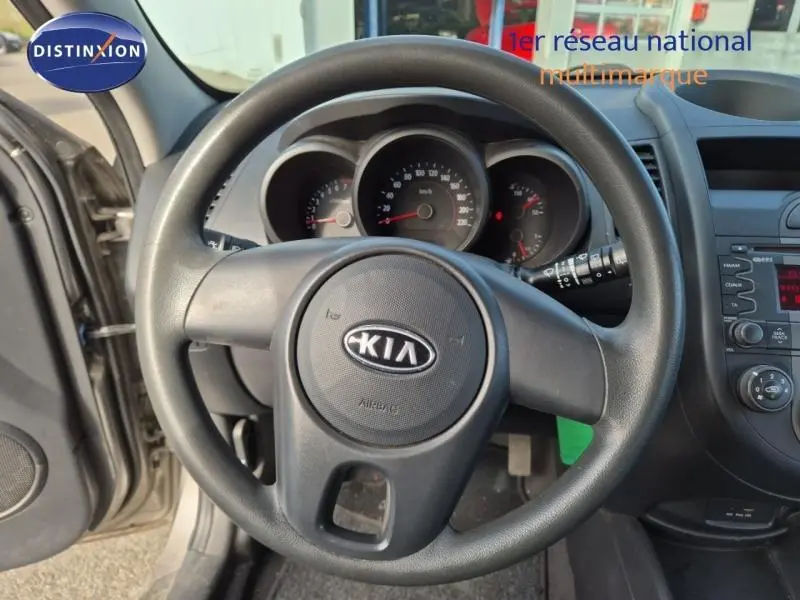 Vue intérieure centrée sur le volant noir de la KIA Soul 2010 avec tableau de bord et commandes visibles.