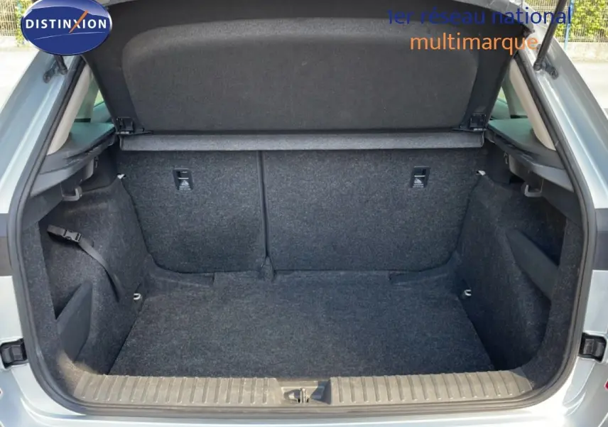 Coffre ouvert vu de l'arrière d'un Skoda Kamiq gris argent métal, montrant l'espace de chargement vide et doublé de tissu gris.