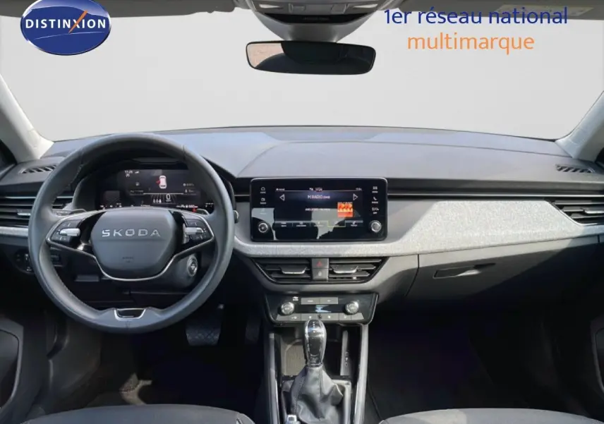 Vue intérieure avant du Skoda Kamiq gris argent, mettant en valeur le tableau de bord moderne et l’écran tactile central.