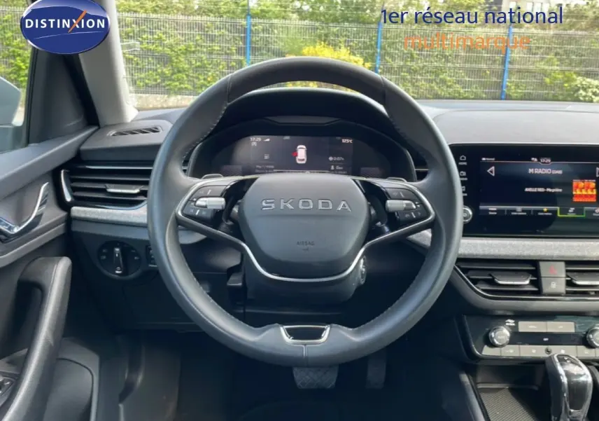 Vue intérieure centrée sur le volant cuir SKODA d'un KAMIQ gris argent 2025, avec tableau de bord digital et écran tactile.