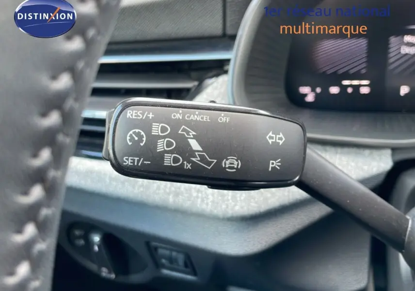 Gros plan sur la commande de régulateur de vitesse à gauche du volant dans l’habitacle du Skoda Kamiq gris argent.