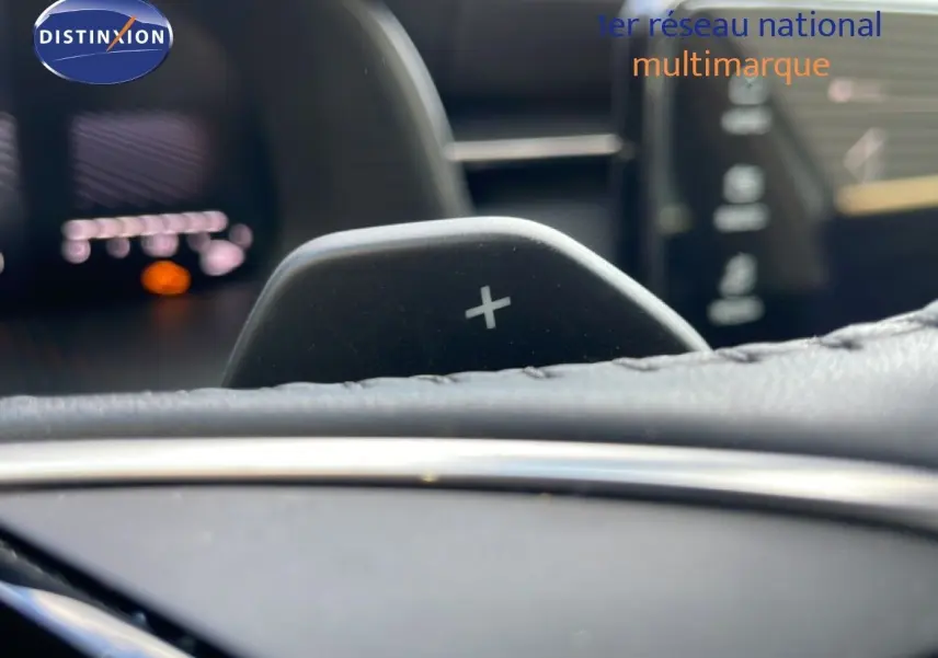 Gros plan sur la palette de changement de vitesse + du Skoda Kamiq 2025, intérieur cuir noir avec tableau de bord flou.