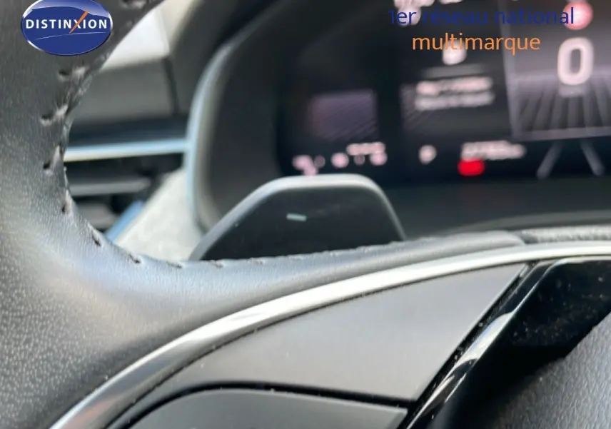 Gros plan sur le volant cuir noir du Skoda Kamiq 2025 avec commandes intégrées et tableau de bord numérique flou en arrière-plan.