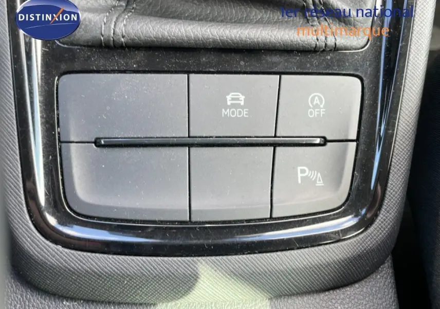 Gros plan sur les boutons de commande du mode de conduite et du stationnement assisté dans une Skoda Kamiq gris argent 2025.