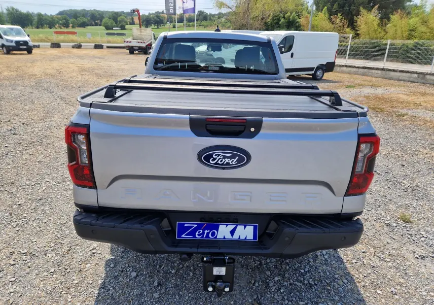 Vue arrière d'un Ford Ranger Super Cabine gris Iconic avec rideau de plateau rigide et attelage visible.