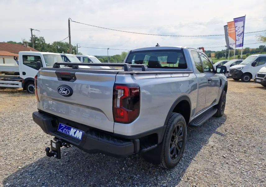 Vue 3/4 arrière droite du Ford Ranger Super Cabine gris Iconic avec barre de plateau et attelage visible.
