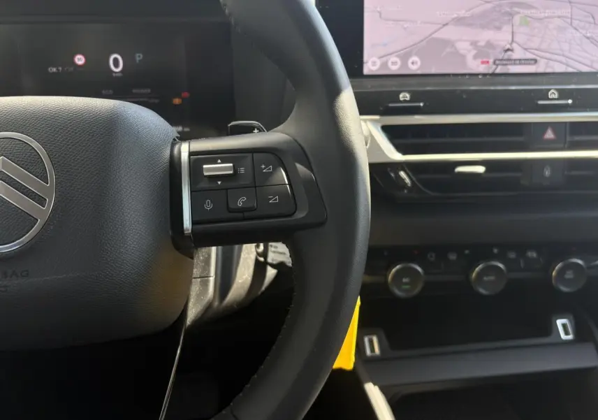 Gros plan sur le volant et tableau de bord du Citroën C4 Hybrid 2025, avec écran tactile de navigation visible.