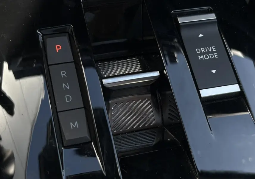 Gros plan sur la console centrale noire brillante avec commandes de boîte auto et bouton Drive Mode de la Citroën C4 Hybrid 2025.