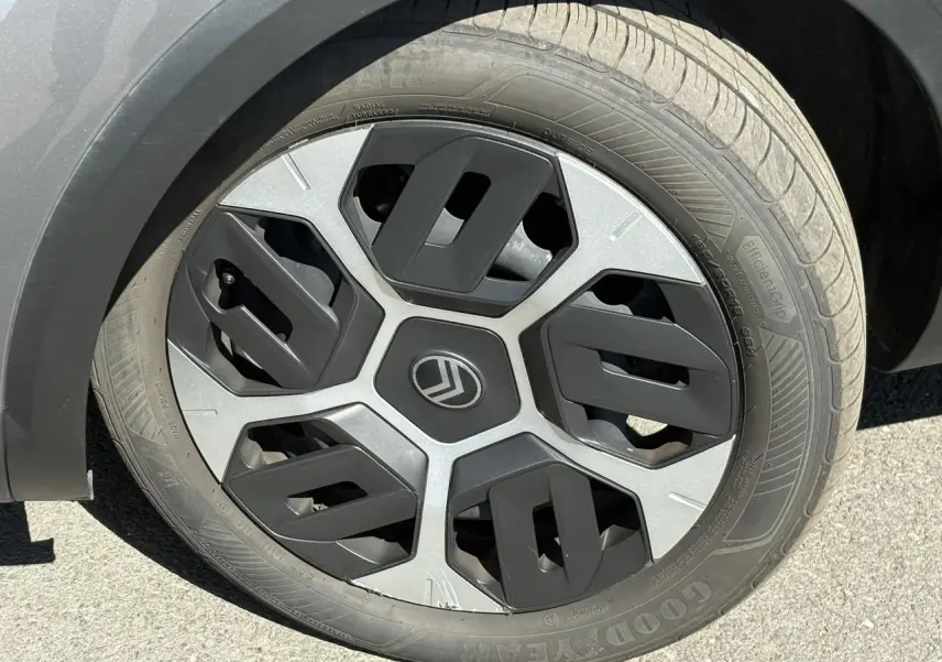 Gros plan sur la roue avant droite d'une Citroën C4 Hybrid 145 gris Mercury avec jante au design géométrique noir et argent.