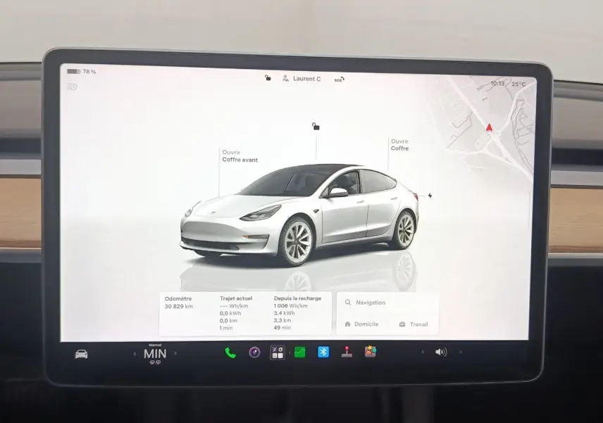Écran tactile central montrant une Tesla Model 3 blanche en 3/4 avant droit avec interface de contrôle et navigation.