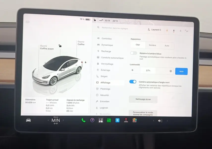 Écran tactile central affichant les réglages et la vue 3/4 avant d’une Tesla Model 3 blanche 2022 Grande Autonomie.
