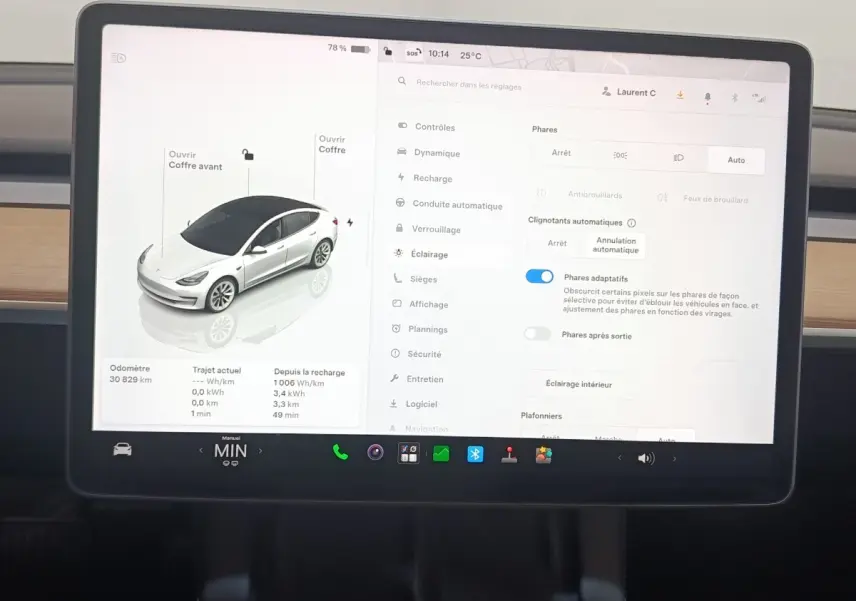 Écran tactile central de Tesla Model 3 blanc 2022 montrant les réglages d’éclairage et l’icône de la voiture en vue 3/4 avant.