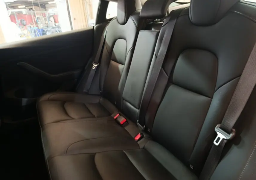 Vue intérieure de la banquette arrière en cuir noir du Tesla Model 3 Grande Autonomie 2022, avec ceintures de sécurité visibles.