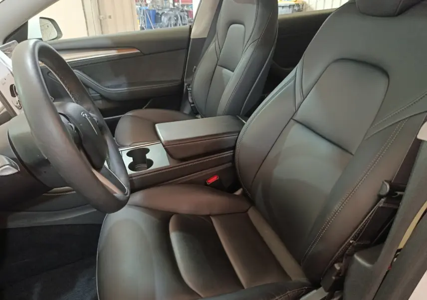 Intérieur de la Tesla Model 3 Grande Autonomie 2022, vue côté conducteur sur sièges en cuir noir et volant multifonction.