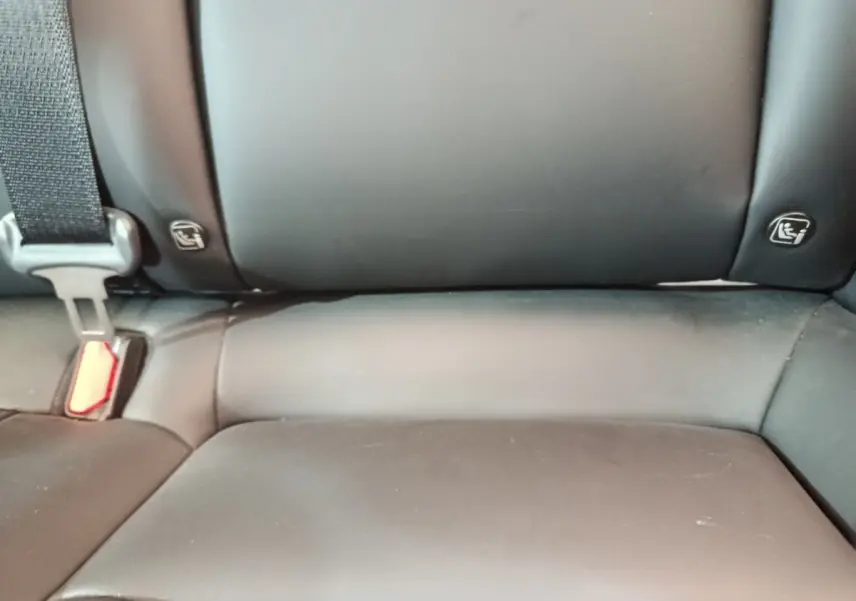 Gros plan sur la banquette arrière noire de la Tesla Model 3 Grande Autonomie 2022, avec ceintures et ancrages Isofix visibles.