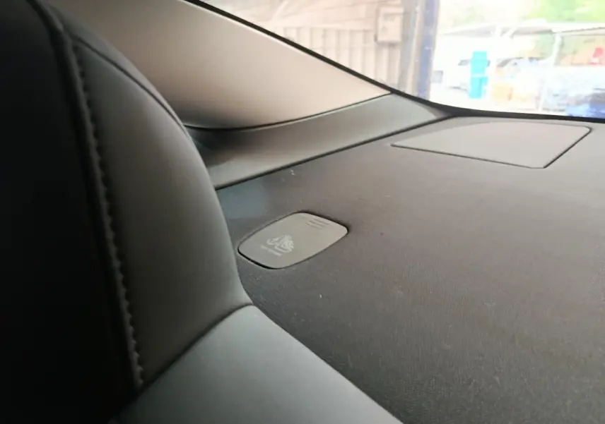 Détail intérieur du tableau de bord noir de la Tesla Model 3 2022, avec zone de recharge par induction visible.