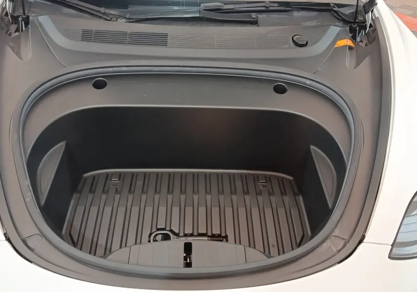 Coffre avant ouvert d'une Tesla Model 3 Grande Autonomie blanche, vue plongeante sur l'espace de rangement vide.