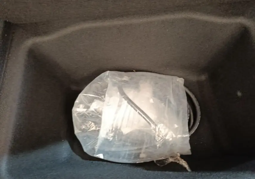 Gros plan sur le coffre avant noir d'une Tesla Model 3 blanche, montrant un câble de recharge emballé.