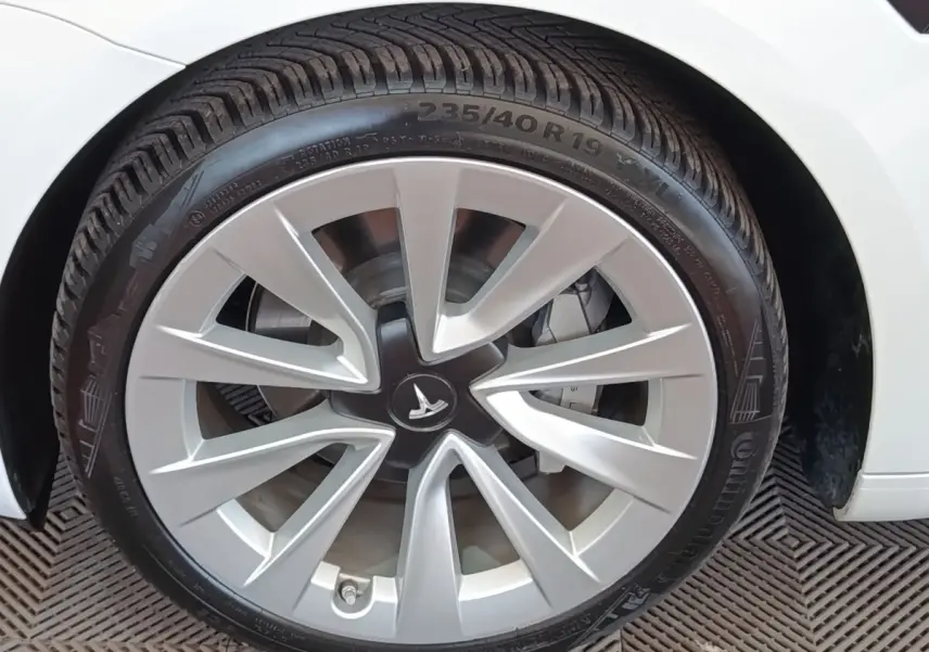 Gros plan sur la roue avant gauche blanche d'une Tesla Model 3 Grande Autonomie 2022 avec jante argentée distinctive.