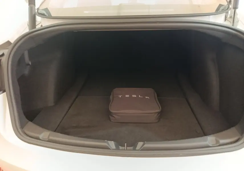 Coffre ouvert d'une Tesla Model 3 blanche 2022, vue de face, avec sac de rangement Tesla noir à l'intérieur.