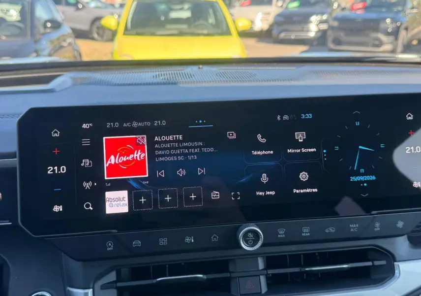 Écran tactile central du Jeep Compass 2026 affichant la radio et les commandes climatisation, intérieur moderne noir.