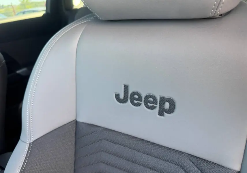 Gros plan sur le siège avant gris clair et noir avec logo Jeep brodé, intérieur du Jeep Compass 2026.
