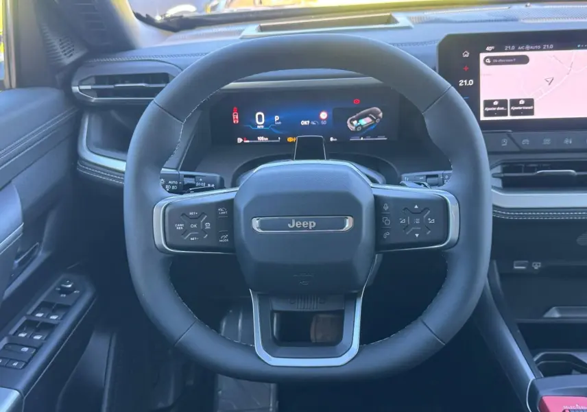 Vue intérieure centrée sur le volant Jeep noir avec tableau de bord numérique et écran tactile à droite
