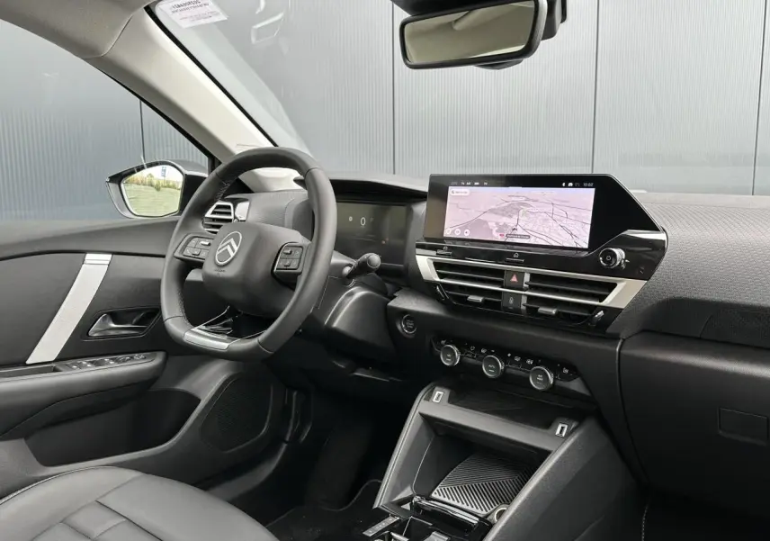 Intérieur avant droit de la Citroën C4 Manhattan Green 2025, avec écran tactile GPS et volant cuir noir.