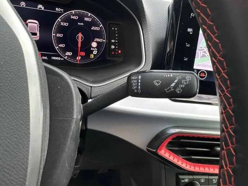 Vue rapprochée du combiné d'instruments et du commodo d'essuie-glace d'une SEAT Ibiza blanc Nevada métal, avec détails rouges sur la console.