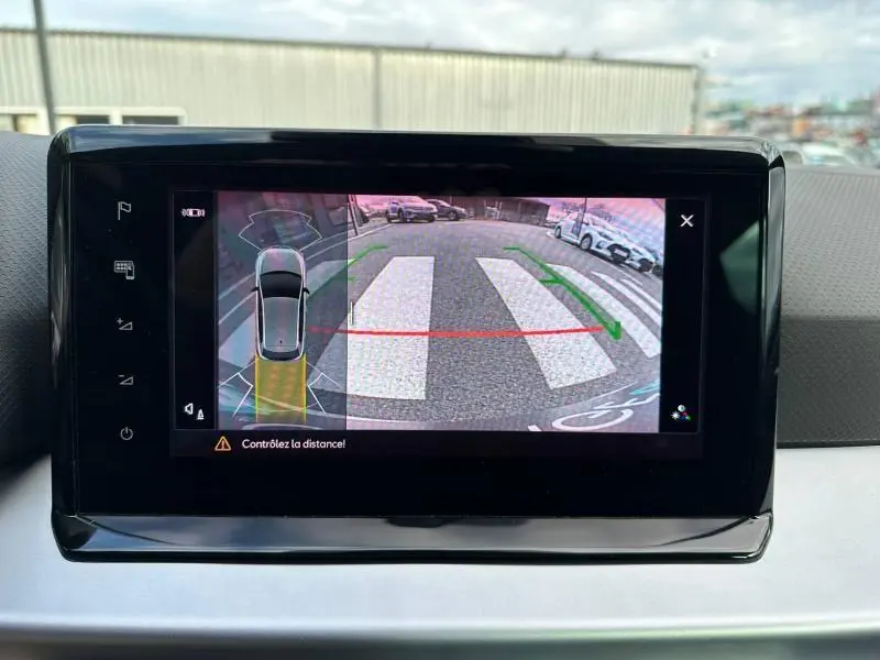 Écran de caméra de recul dans une SEAT Ibiza 2025 blanche, montrant une vue arrière avec marquages au sol et véhicules stationnés.